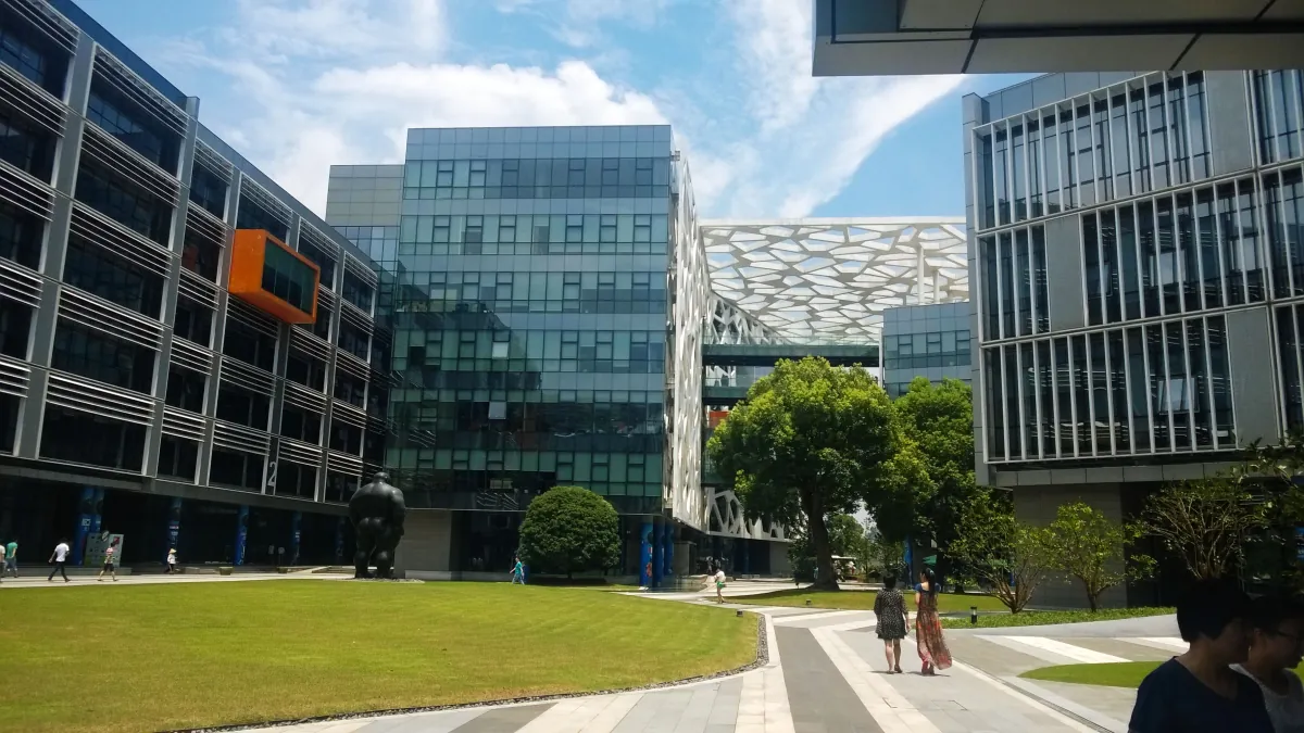 Glass-fronted buildings surrounding a lawn and walkway at Alibaba's Binjiang campus.