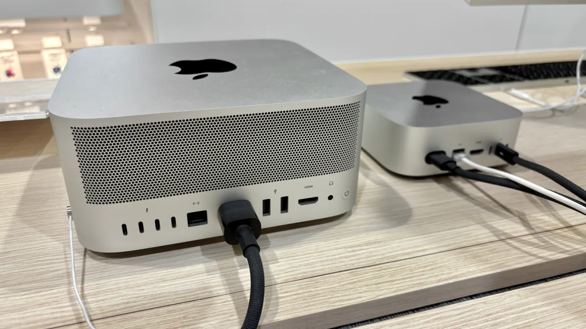 A silver 2024 Mac mini positioned beside a taller Mac Studio on a retail display table.