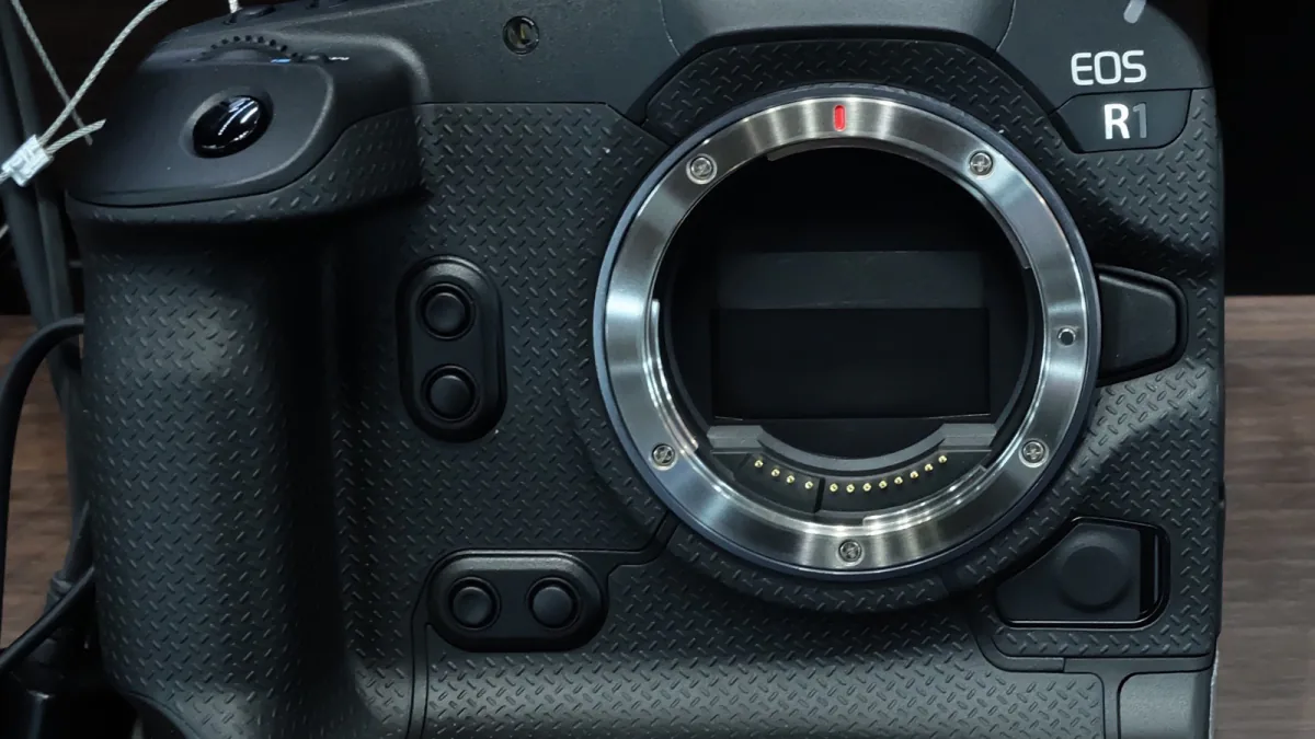 Front view of a black Canon EOS R1 camera body without a lens attached.
