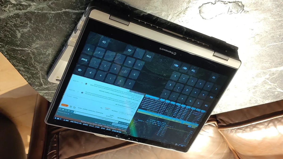An original-generation Framework Laptop 12 folded into tablet mode with Linux applications visible on its touchscreen.