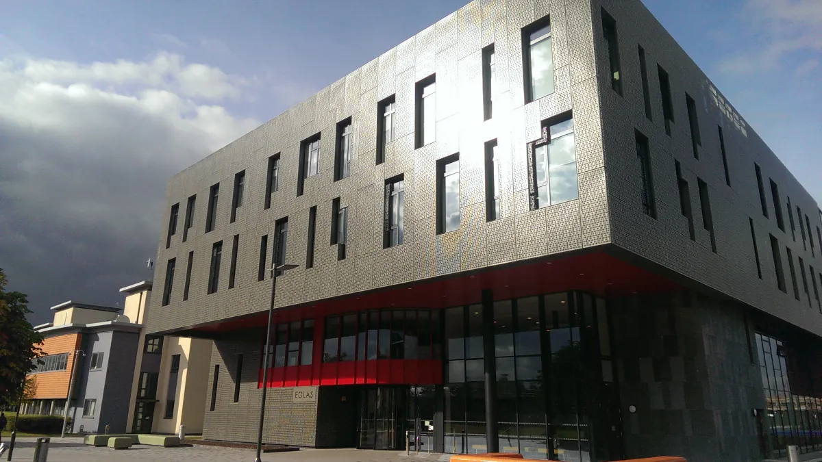 The angular Eolas university building with a patterned metal facade, tall windows and a red band above its entrance.