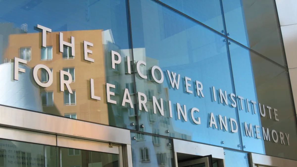 The Picower Institute for Learning and Memory lettering on reflective glass above an entrance.