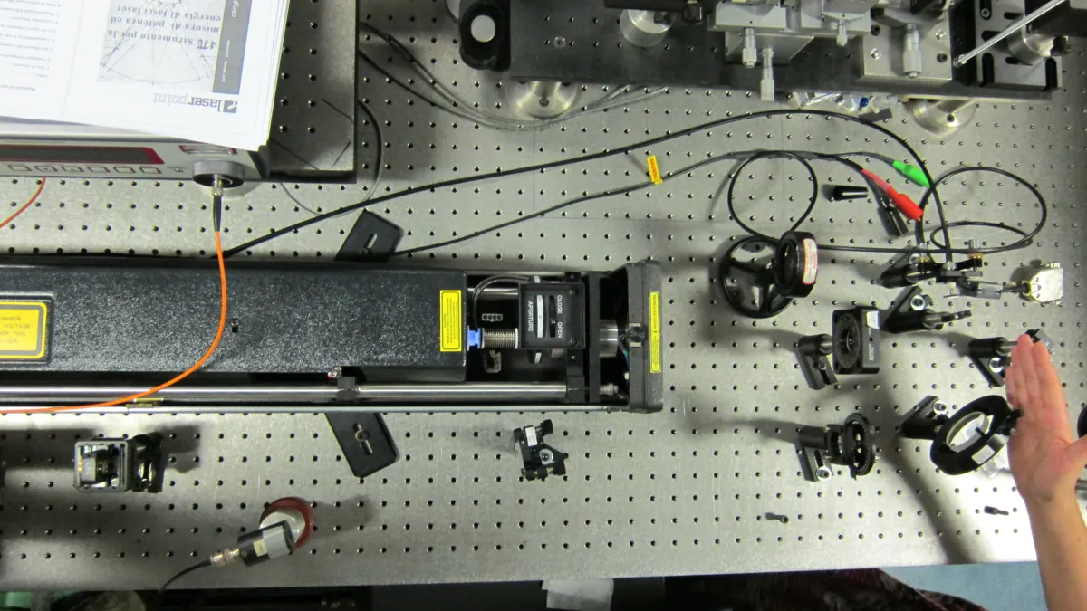 An overhead view of an optical table with mounted lenses, cables and laser equipment.