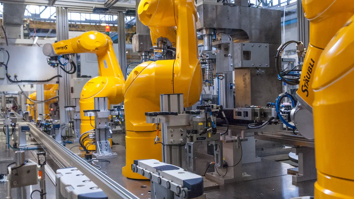 Yellow Stäubli robot arms positioned around machinery on an industrial production line.