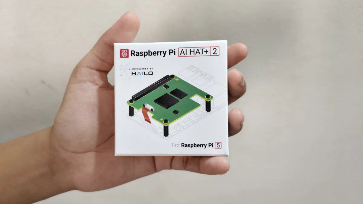 A hand holding the retail box for Raspberry Pi's AI HAT+ 2 add-on board.